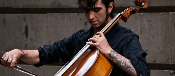 man with a tatoo on his forearm plays a cello