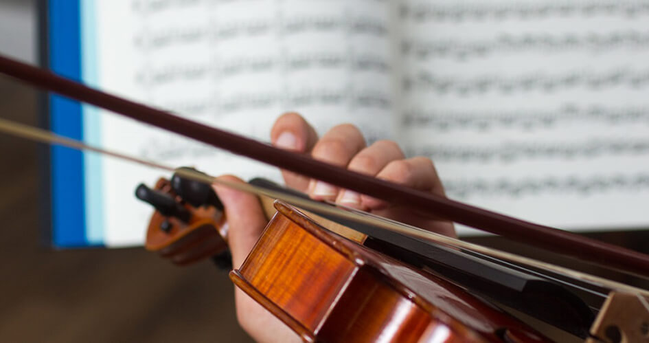 Close-up of violin being played with sheet music in the background