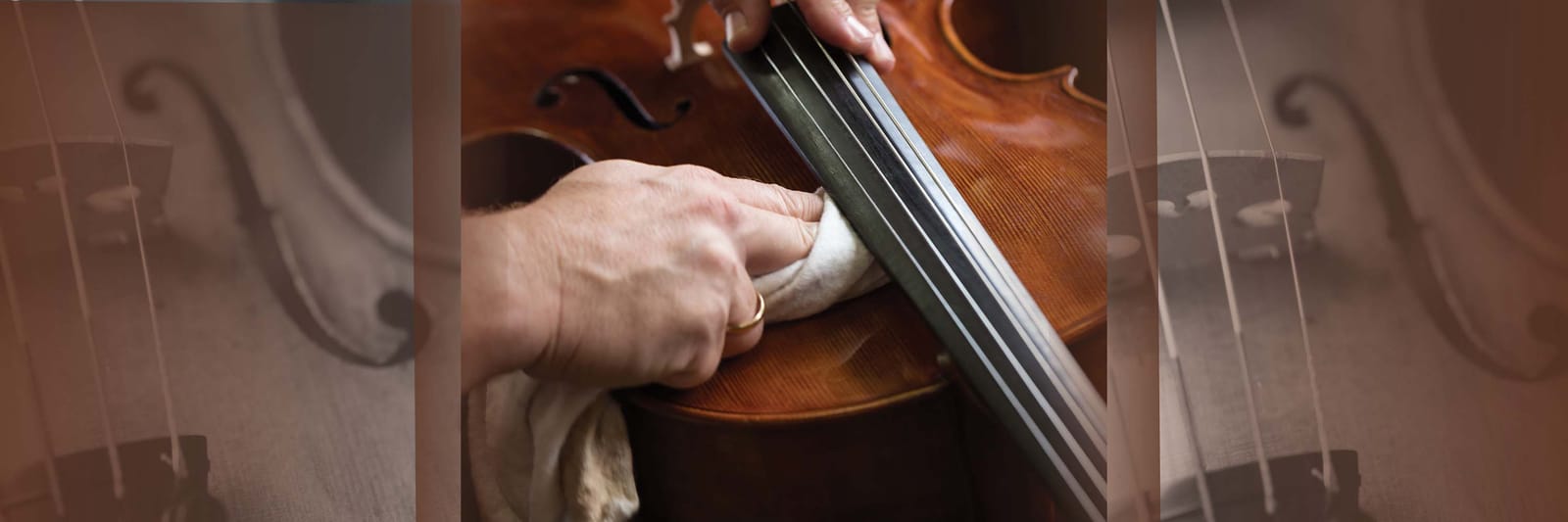 Hands cleaning rosin from a violin fingerboard and body with a soft cloth