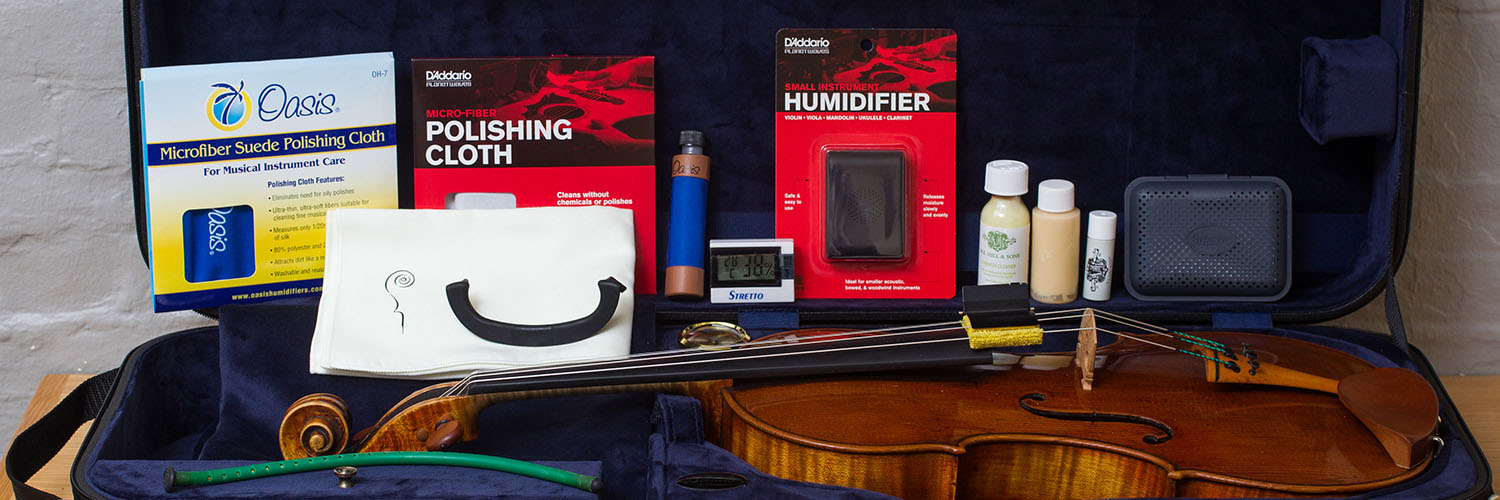 Open violin case with accessories including humidifier, polishing cloth, and cleaning products