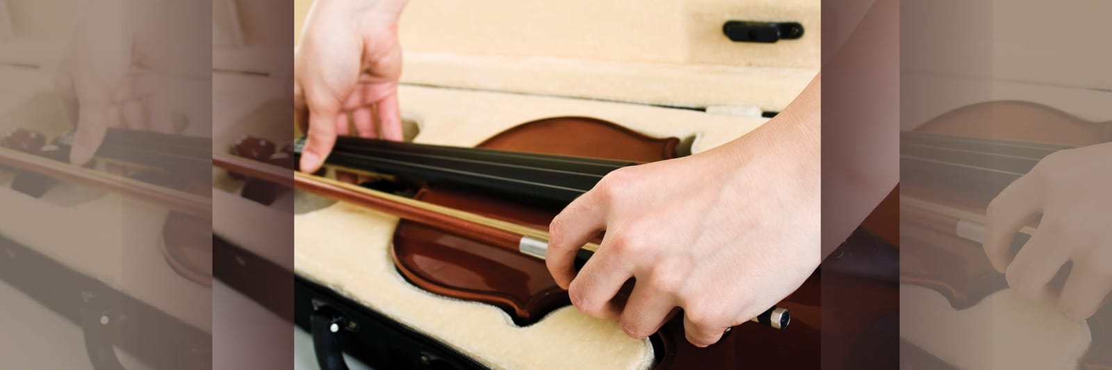 Hands placing a violin and bow into a padded instrument case