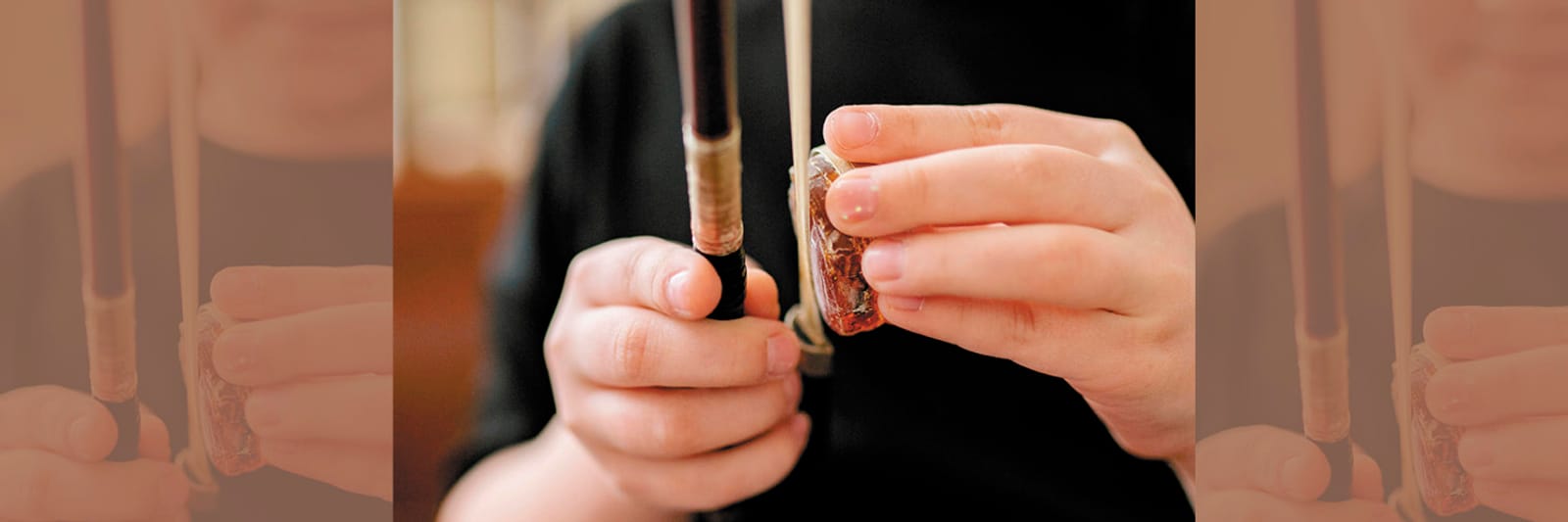 Hands applying rosin to a violin bow
