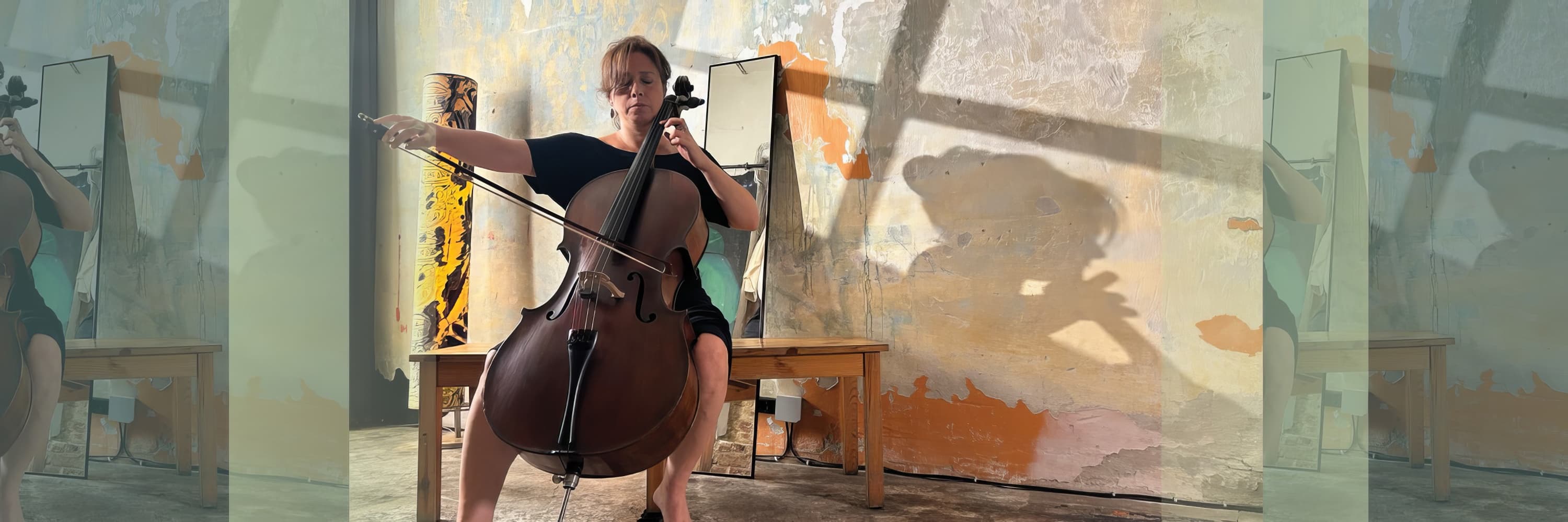 Woman playing cello in front of a textured wall with dramatic lighting and shadows