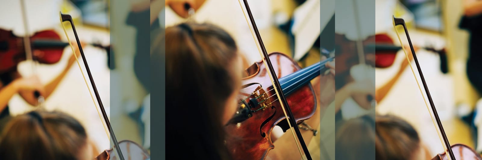 Student playing a violin with bow during a music class, focused on instrument and technique