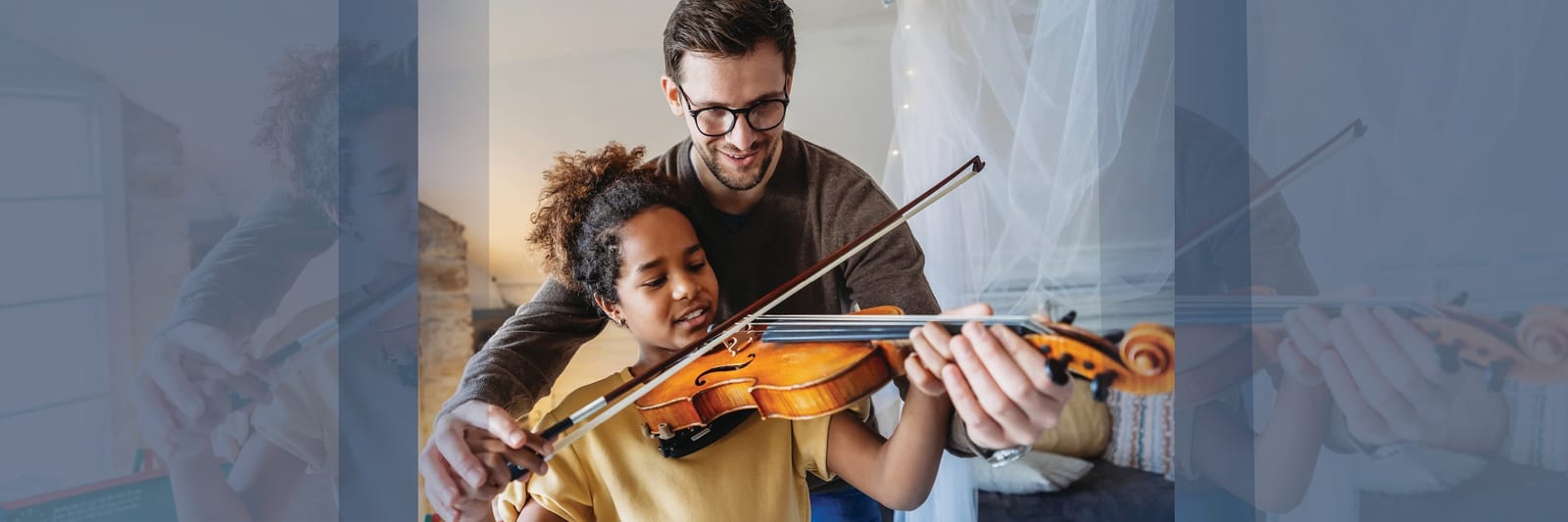 Man teaching a young girl how to play the violin at home