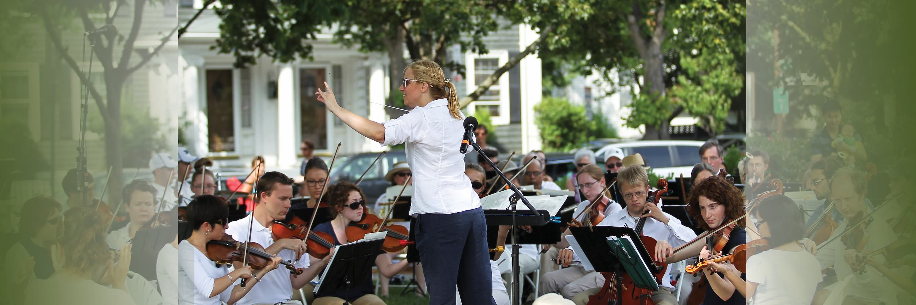 Outdoor orchestra performance with conductor leading musicians playing string instruments