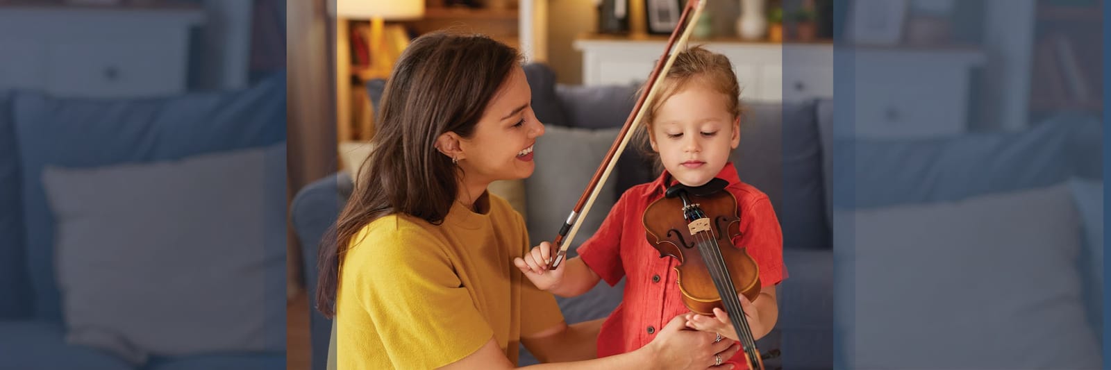 Woman teaching young child to play violin at home