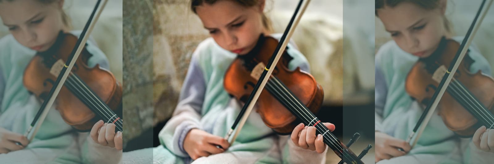 Child practicing violin with focused expression and small hands on the strings