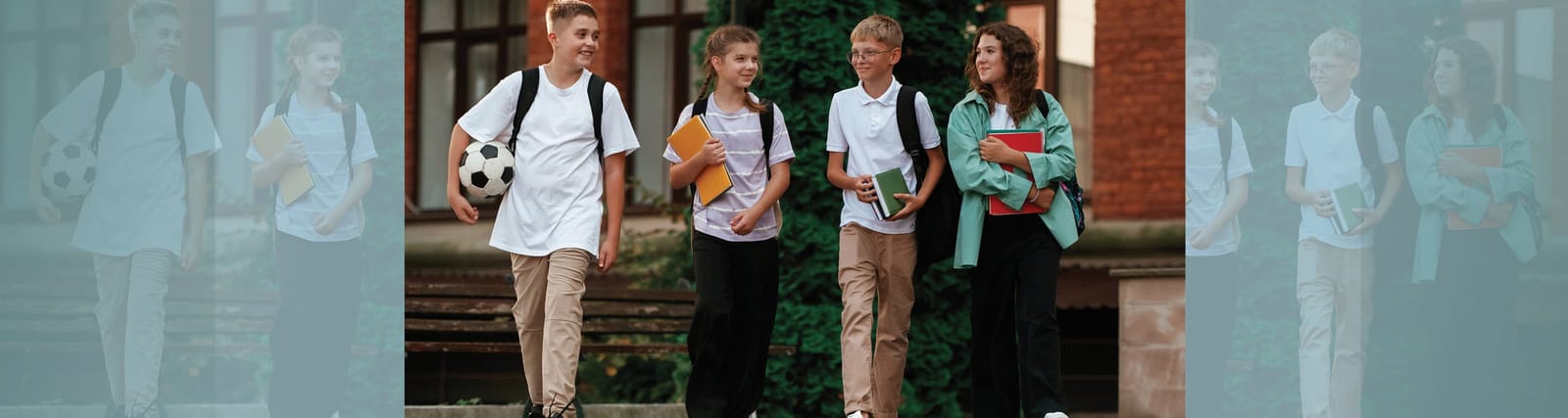Group of four students walking outside with backpacks, books, and a soccer ball