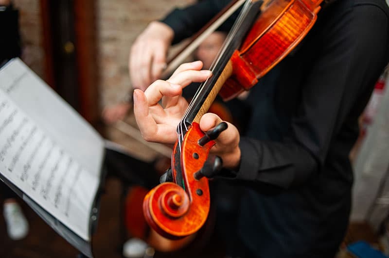 Violinist playing with a music stand in the background