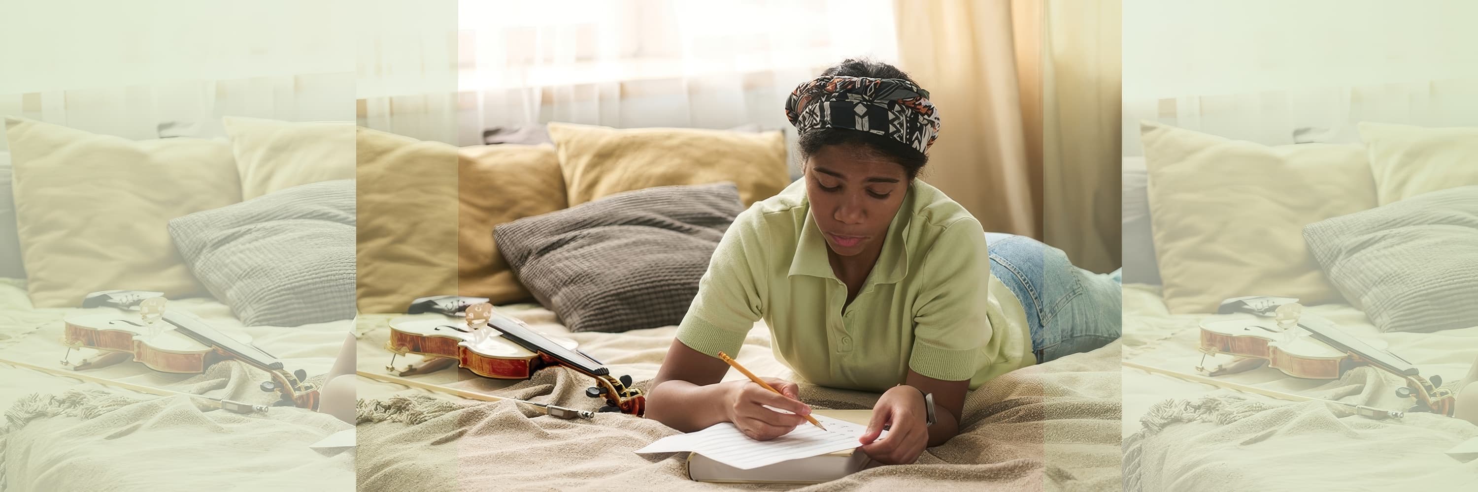 Young woman lying on bed writing in notebook with a violin and bow beside her