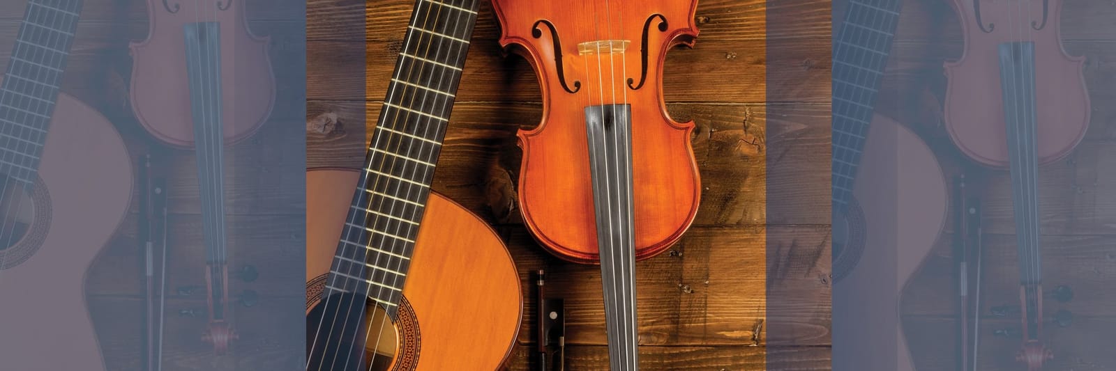 Acoustic guitar and violin placed side by side on a wooden surface