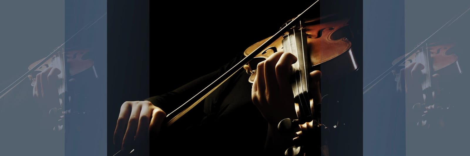 Person playing a violin with a bow under dramatic lighting