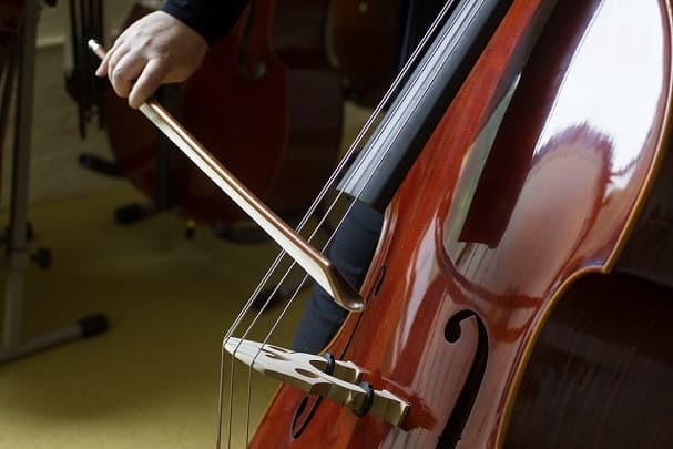 Close-up of a person playing a double bass with a bow