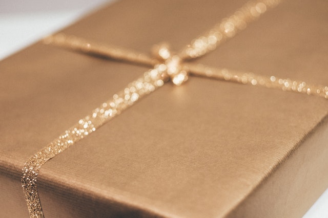 Close-up of a gift wrapped in gold paper with a glittery ribbon.