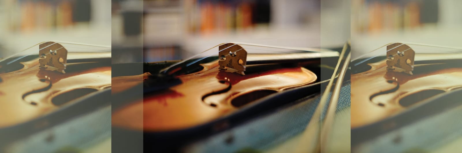 Close-up of a violin body with strings and bridge in soft warm lighting