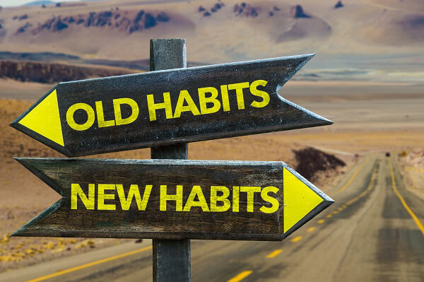 Old wooden road sign that reads Old habits, new habits