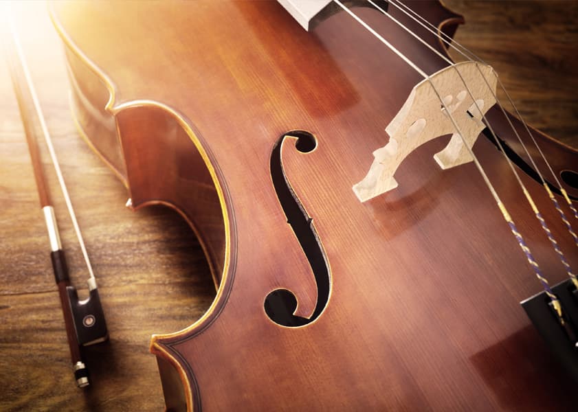 cello laying on a wooden table with a bow
