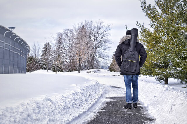 Man walking away down a path in winter with a soft-case on his back