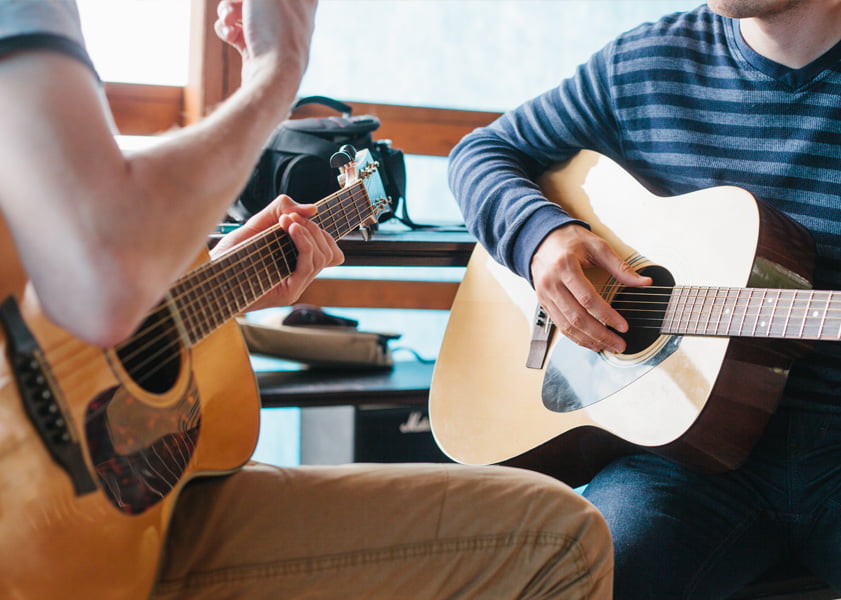 two people playing guitars