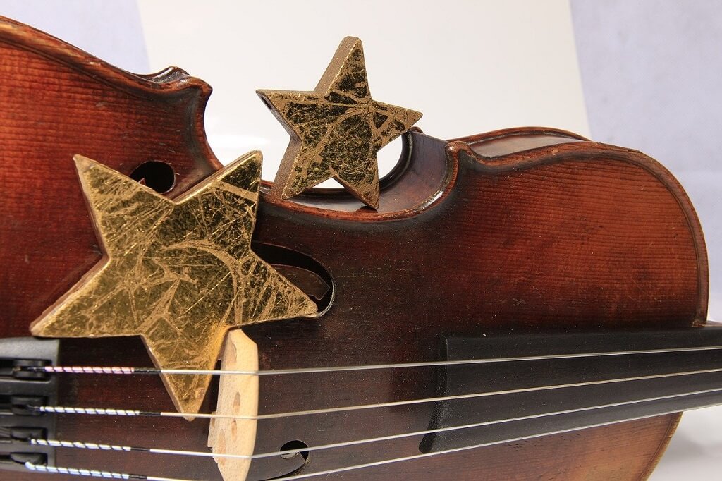 Closeup of a violin laying on its side with two glod stars placed on top.