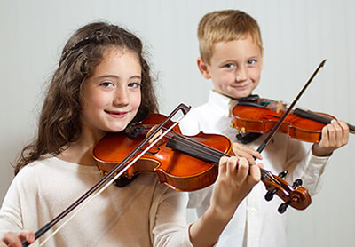 Young girl and boy playing violins