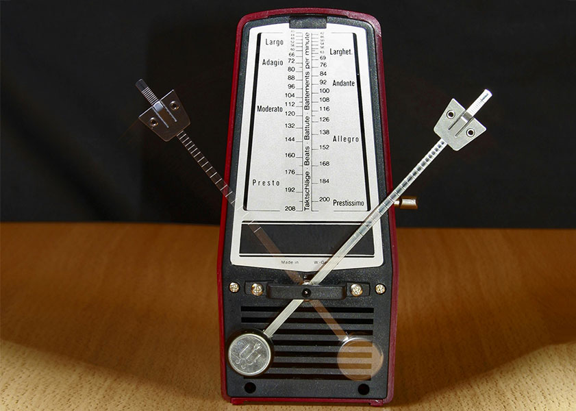 Mechanical metronome with a moving pendulum, showing tempo markings from Largo to Prestissimo on a black and red background.