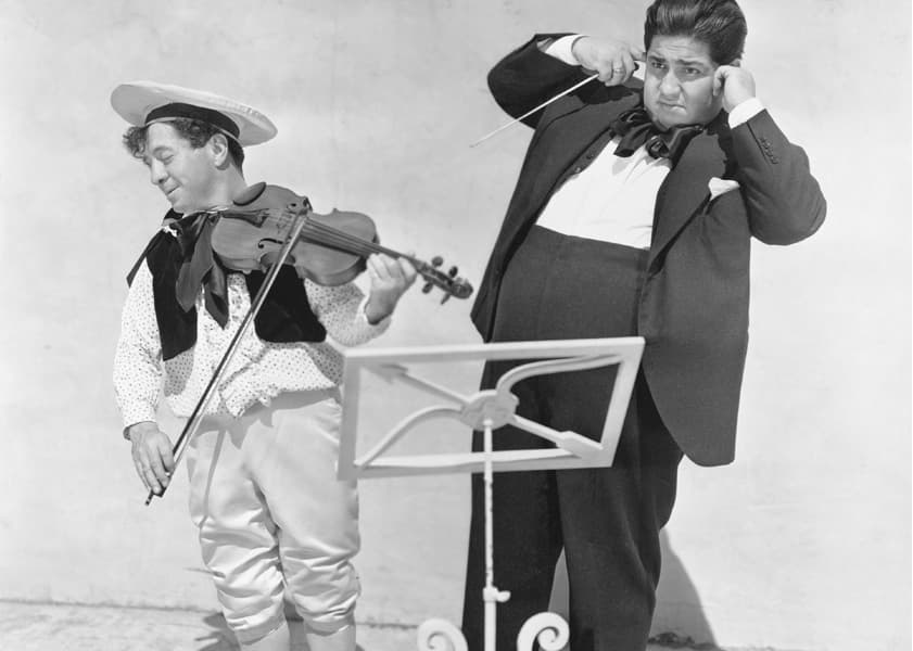 black and white photo of two comedians playing violin
