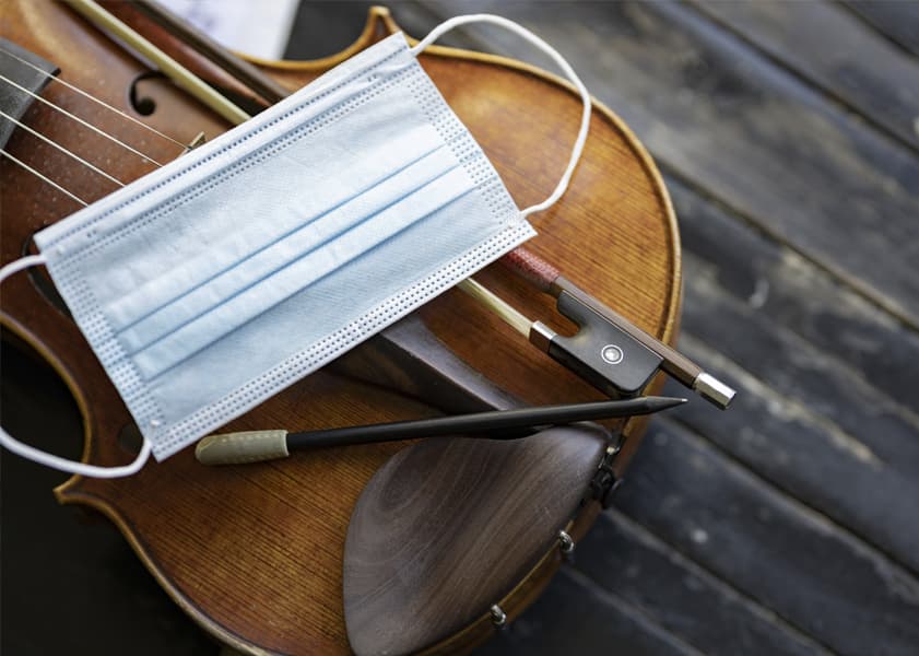 Protective face mask laying on top of a violin