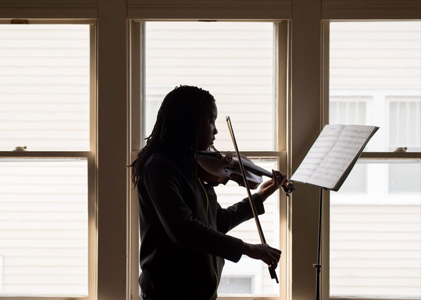 woman plans violin on front of window