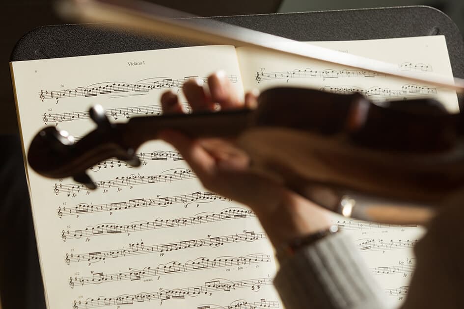 Violin in the foreground and sheet music on a stand in the background